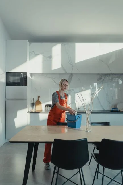 A couple wrapping furniture in a bright apartment, preparing to move.
